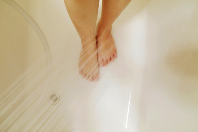 足を冷たいシャワーで流す女性